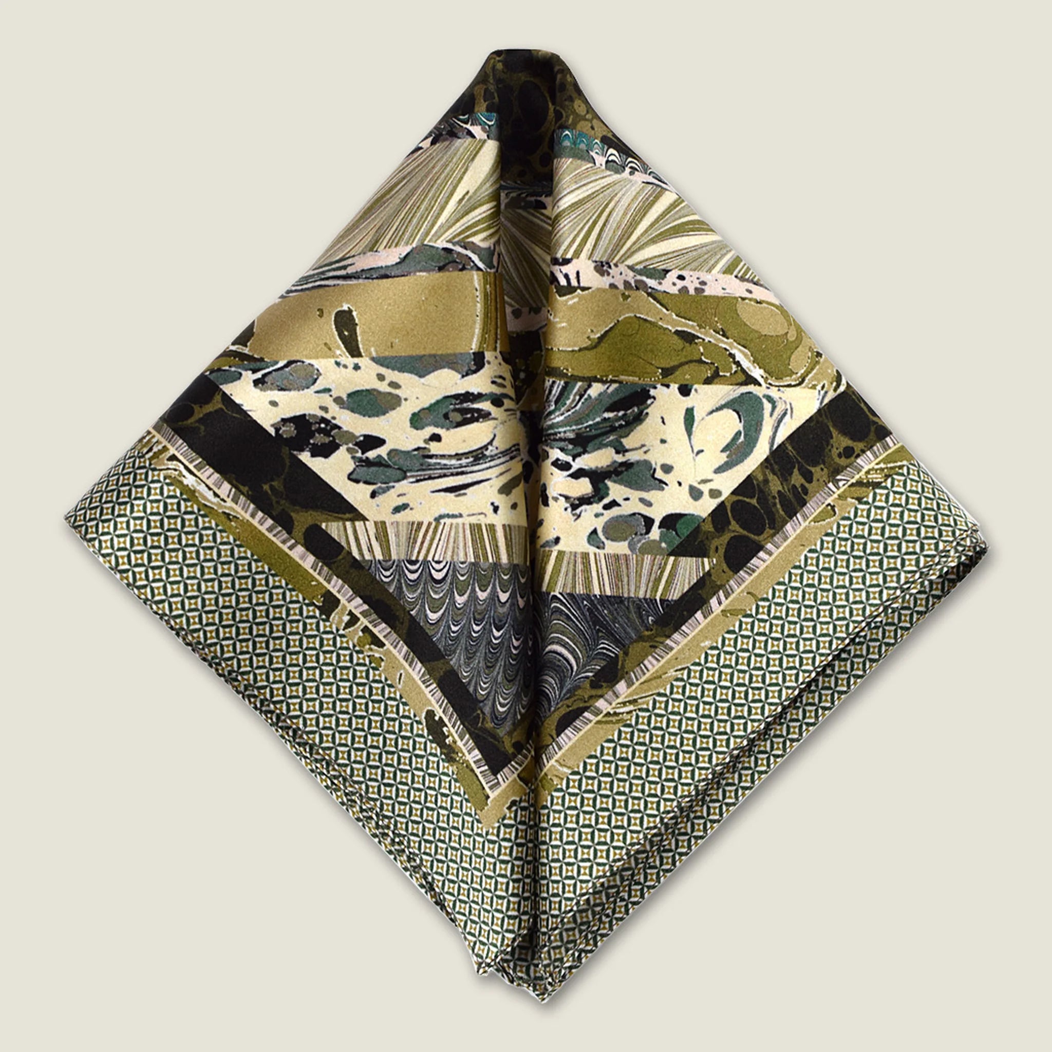 This Marble Camo pocket square applies the flowing, layered quality of traditional hand-marbling to a palette of olive green, teal, black and ivory. Photographed folded into two triangles. 
