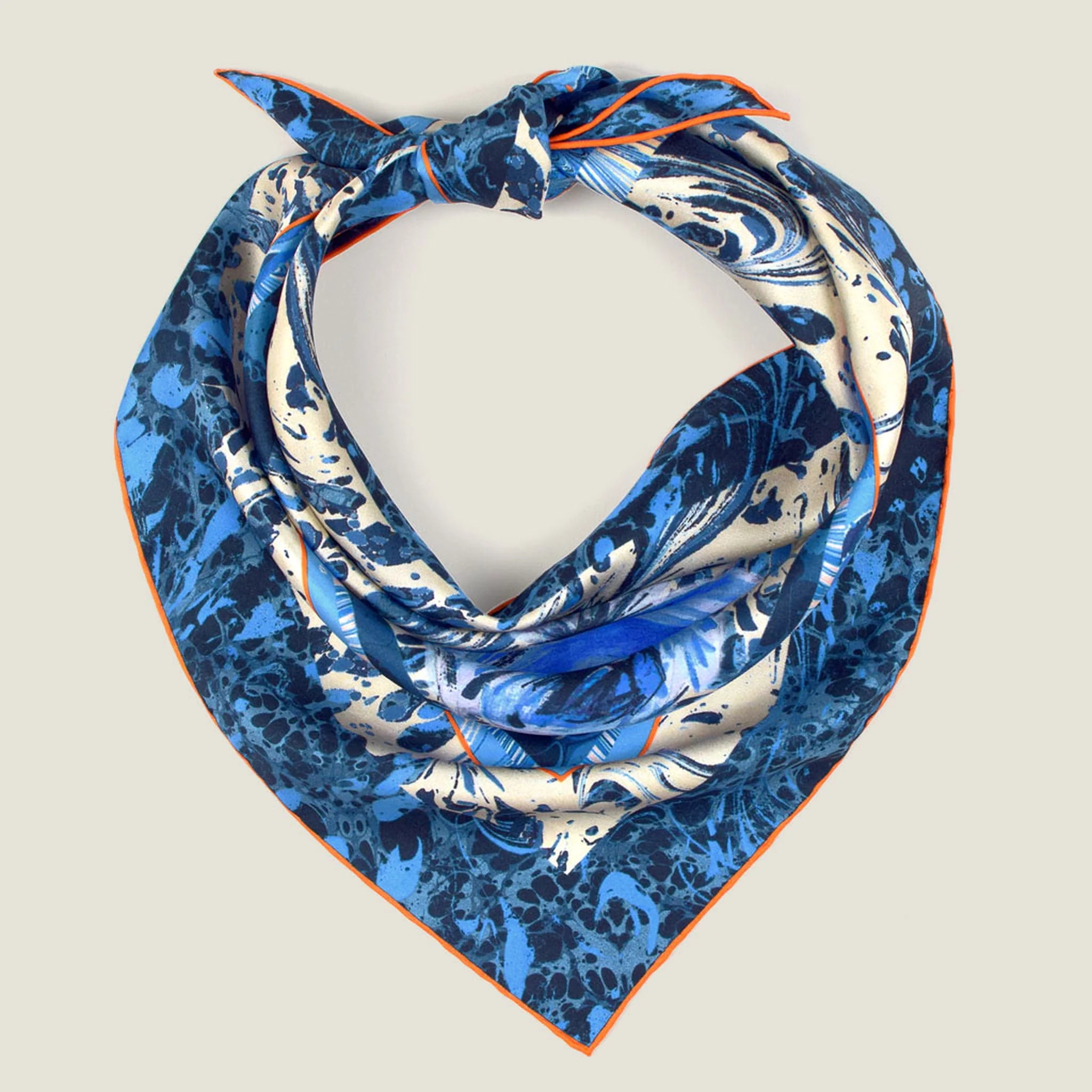 100% silk Marble Rose Triangle Scarf in blue by Laslett England shown against a neutral background with a tie behind the back and a rumpled drape. 