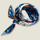 100% silk Marble Rose Triangle Scarf in blue by Laslett England shown on a neutral background. The scarf is looped and then tied into a knot. 