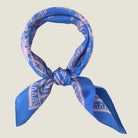 Laslett England Marettimo Cornflower Blue Bandana tied into a cowboy not against a neutral background. The pink pattern is inspired by botanical and coastal elements. 