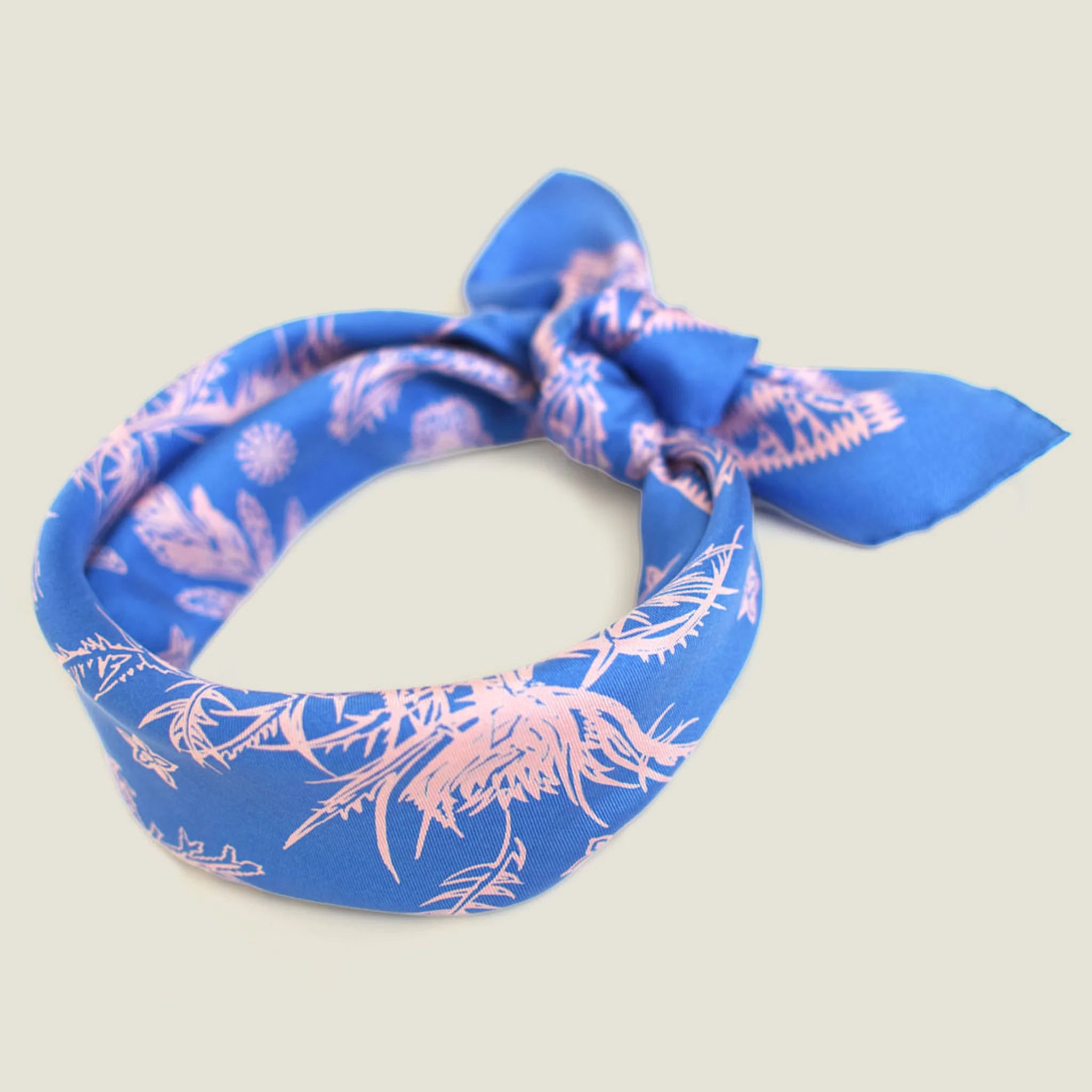 Laslett England Marettimo Cornflower Blue Bandana tied into a knot  at the back against a neutral background. The pink pattern is inspired by botanical and coastal elements. 