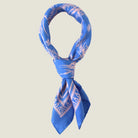 Laslett England Marettimo Cornflower Blue Bandana tied into a knot against a neutral background. The pink pattern is inspired by botanical and coastal elements. 