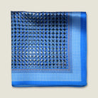100% silk Matrix Blue pocket square has a distinctive geometric and repeating floral print in blue tones. Shown folded in four against a neutral background. 
