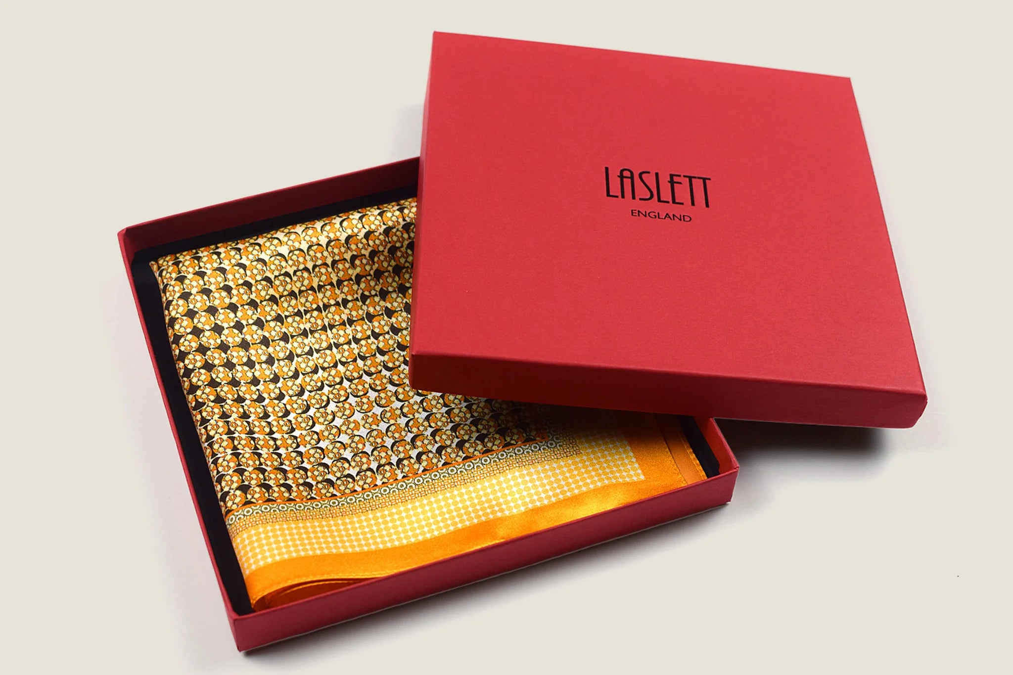 100% silk Matrix Gold Pocket Square has a futuristic geometric design that reveals, on closer inspection, repeating graphic lines and patterns across the surface. Square is shown in a red signature Laslett England box. 
