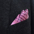This Matrix Pink pocket square has a striking geometric design that reveals, on closer inspection, repeating graphic lines and patterns. In soft dusty pink with charcoal and white, square is shown tucked neatly into a charcoal suit pocket. 