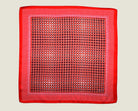 100% Matrix Red pocket square has a geometric design with a floral repeat that reveals itself on closer inspection. Square is shown in flat lay against a neutral background. 