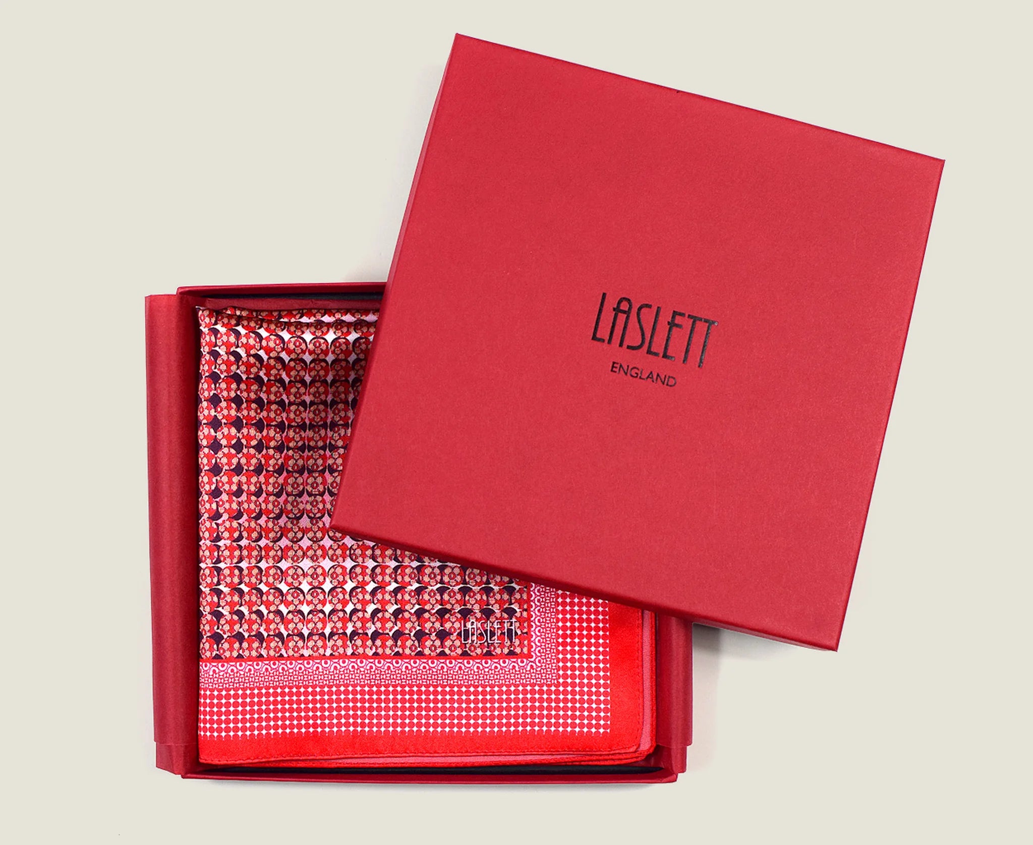 100% Matrix Red pocket square has a geometric design with a floral repeat that reveals itself on closer inspection. Square is shown boxed in a red signature box. 