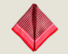 100% Matrix Red pocket square has a geometric design with a floral repeat that reveals itself on closer inspection. Square is shown folded into two triangles against a neutral background. 