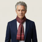 Laslett England Monaco Burgundy Silk Oblong worn looped at neck by male model in navy suit, showing deep burgundy with white dot print and pink stripe border.