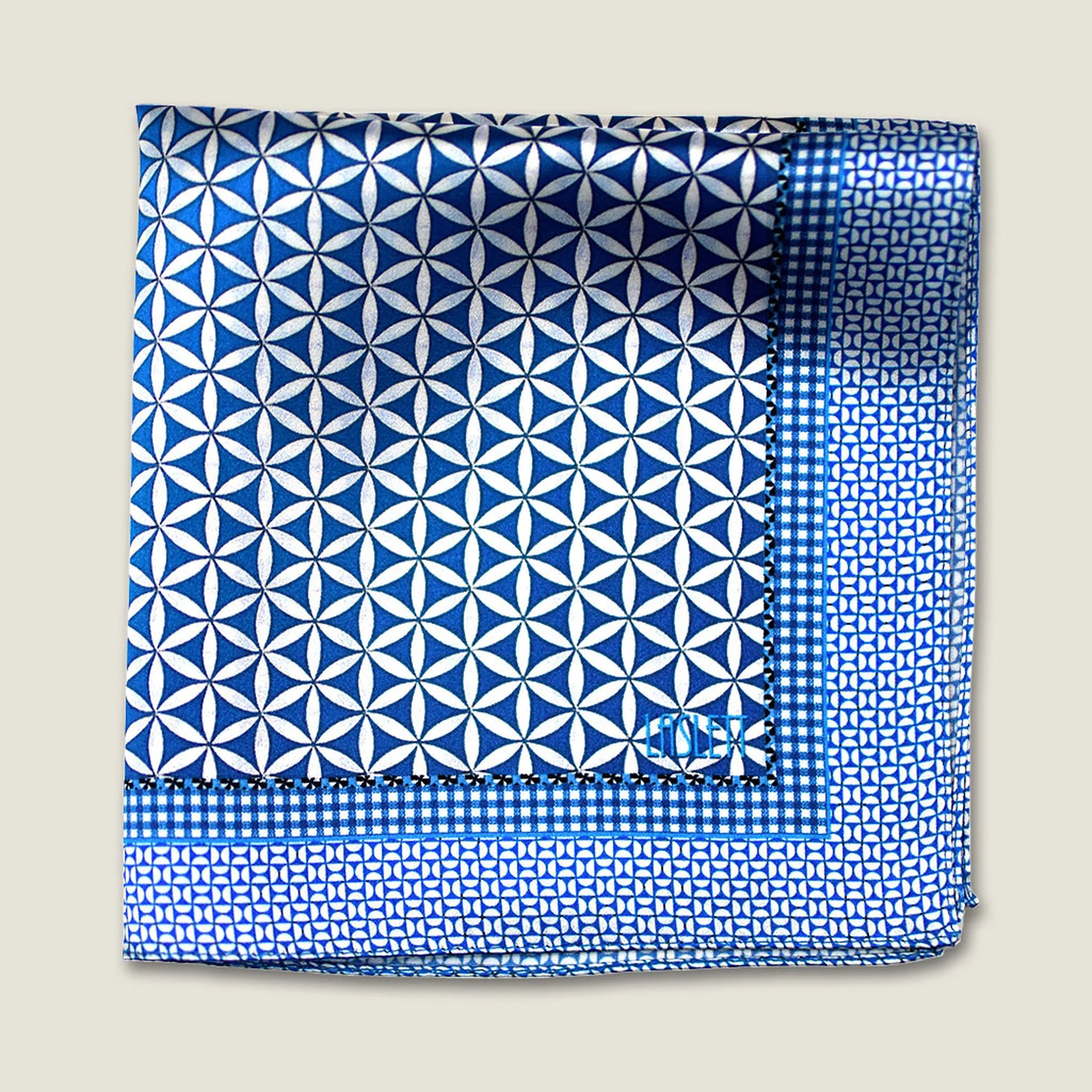 100% silk Moresque Blue pocket square from Laslett England shown folded into four against a neutral background to demonstrate the smaller geometric pattern of the border. 