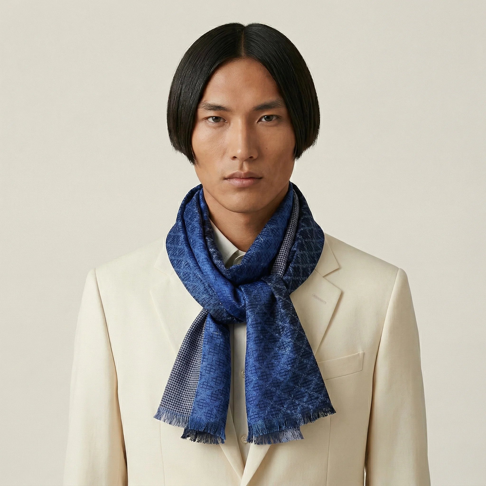100% silk Mosaic Lapis Silk Oblong in blue by Laslett England worn tied around the neck of a model wearing a cream suit. 