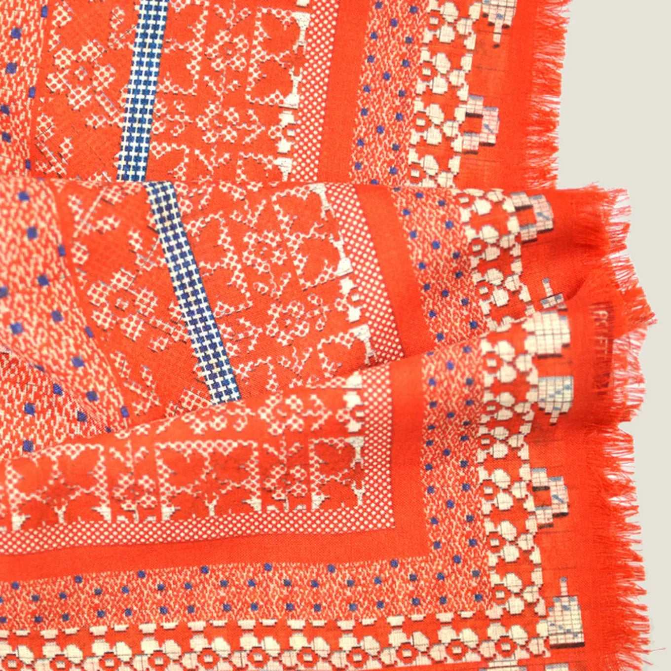Nordic Folk orange silk scarf by Laslett England shown in close-up with a vibrant flower and geometric print with fringed edge. 