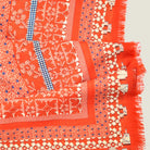 Nordic Folk orange silk scarf by Laslett England shown in close-up with a vibrant flower and geometric print with fringed edge. 