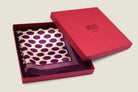Oval Spot Burgundy pocket square from Laslett England is folded into four and displayed in the signature red box. 