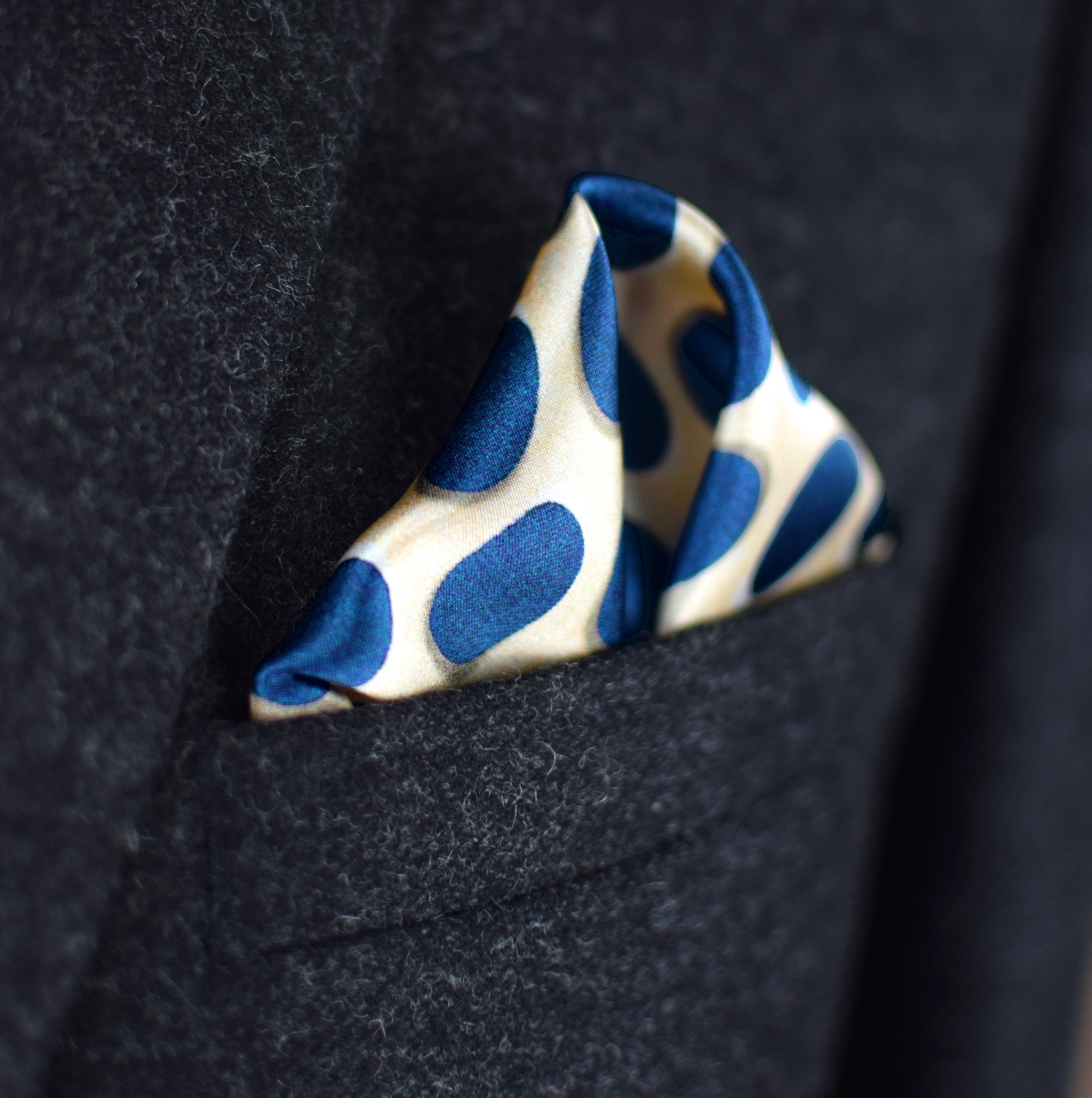 Laslett England Oval Spot Navy pocket square in breast pocket of dark suit, cream silk with large navy oval spot print