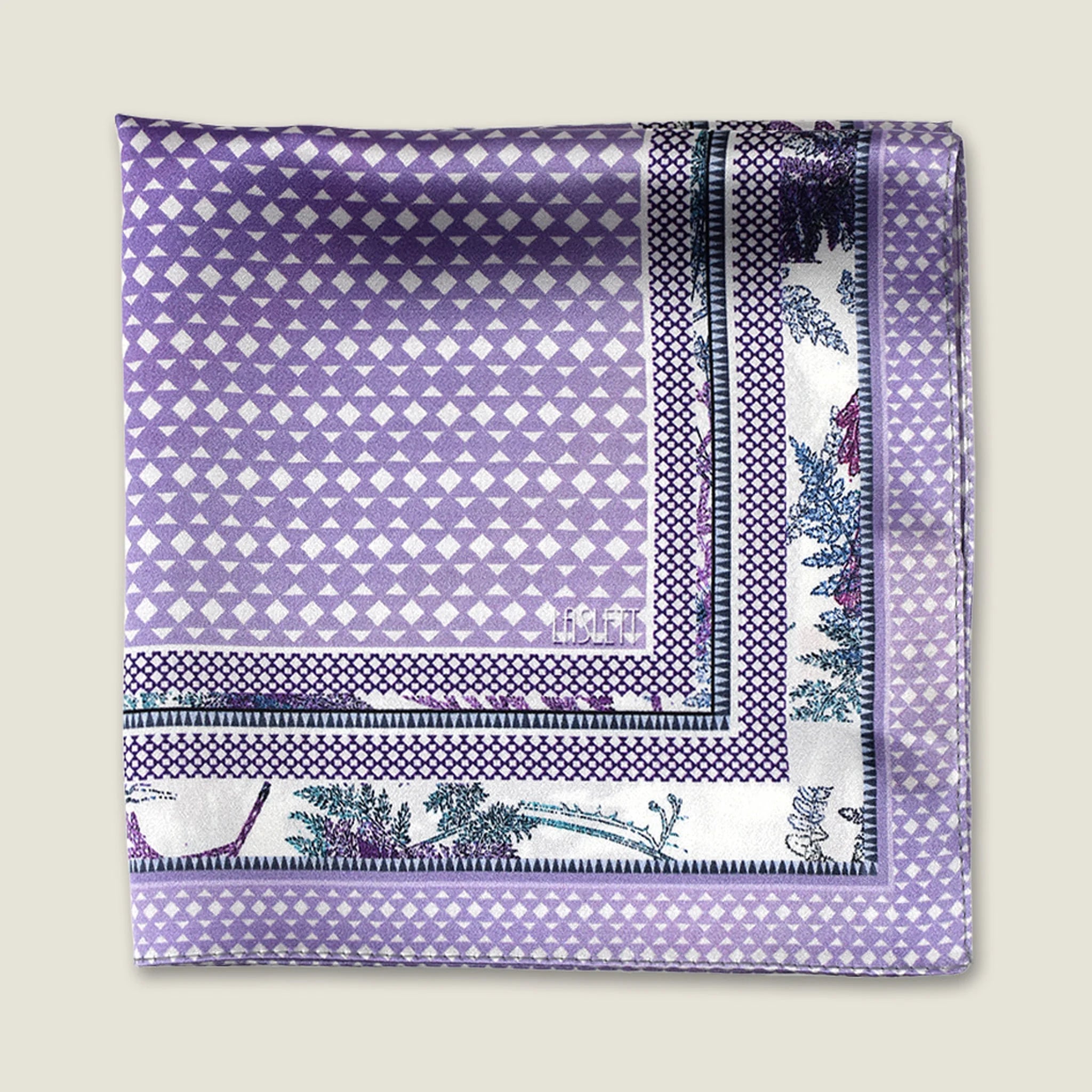 100% silk Panama Lilac pocket square takes its pattern from woven cane and straw, a geometric centre print in soft lilac and white with a botanical border of ferns in complementary tones. Photographed folded into four with the Laslett England logo. 