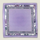 100% silk Panama Lilac pocket square takes its pattern from woven cane and straw, a geometric centre print in soft lilac and white with a botanical border of ferns in complementary tones. Photographed in flat lay. 