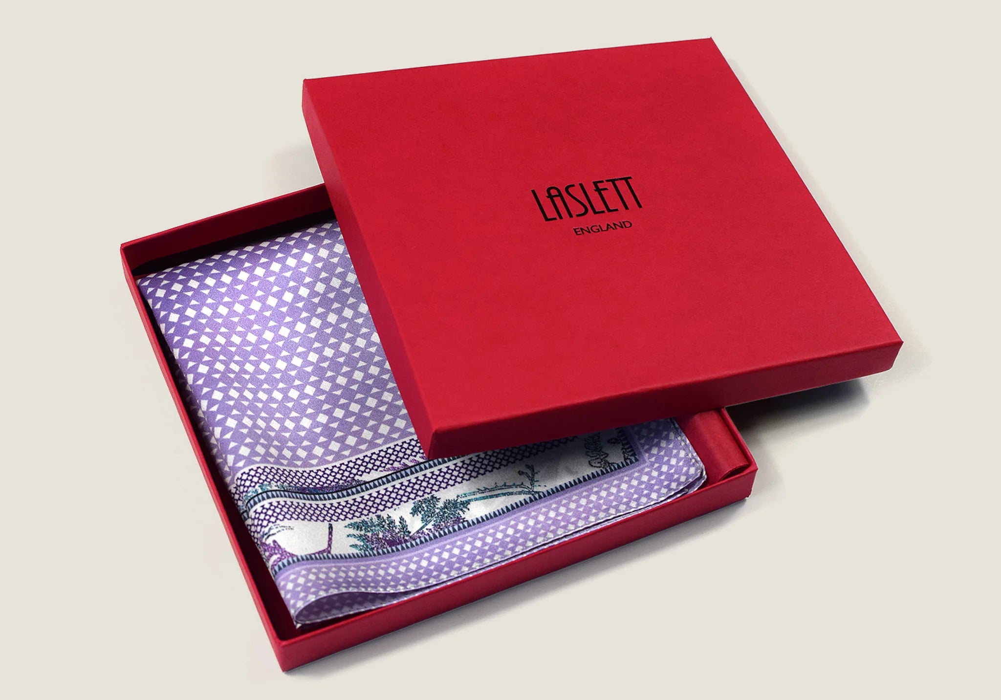 100% silk Panama Lilac pocket square takes its pattern from woven cane and straw, a geometric centre print in soft lilac and white with a botanical border of ferns in complementary tones. Photographed in the signature red Laslett England box. 