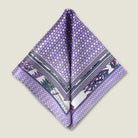 100% silk Panama Lilac pocket square takes its pattern from woven cane and straw, a geometric centre print in soft lilac and white with a botanical border of ferns in complementary tones. Photographed folded into two triangles in flat lay. 