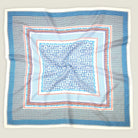 A crumpled flat lay of the Laslett England Regatta Silk Scarf showing the many complimentary geometric square patterns against a neutral background. 