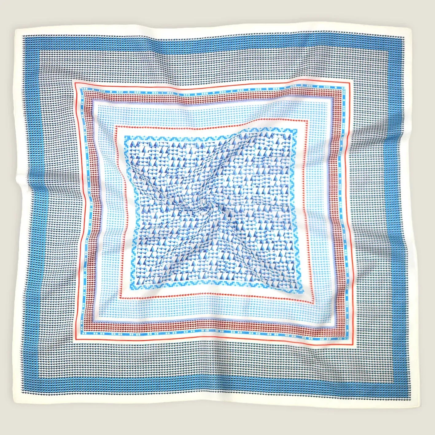 A crumpled flat lay of the Laslett England Regatta Silk Scarf showing the many complimentary geometric square patterns against a neutral background. 