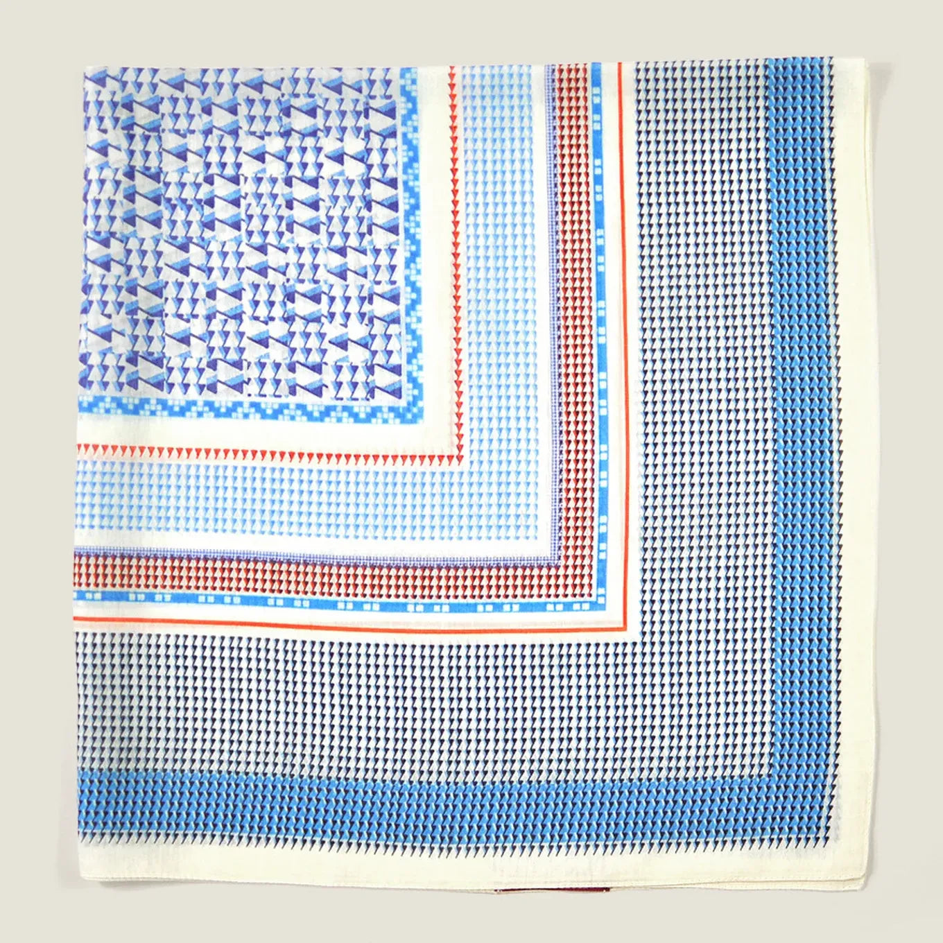 A crumpled flat lay of the Laslett England Regatta Silk Scarf showing the many complimentary geometric square patterns against a neutral background. 