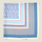 A crumpled flat lay of the Laslett England Regatta Silk Scarf showing the many complimentary geometric square patterns against a neutral background. 