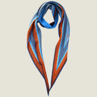 100% silk Sunset Orange Laslett Diamond in orange and blue by Laslett England. Scarf is looped at the neck and shown against a neutral background. 