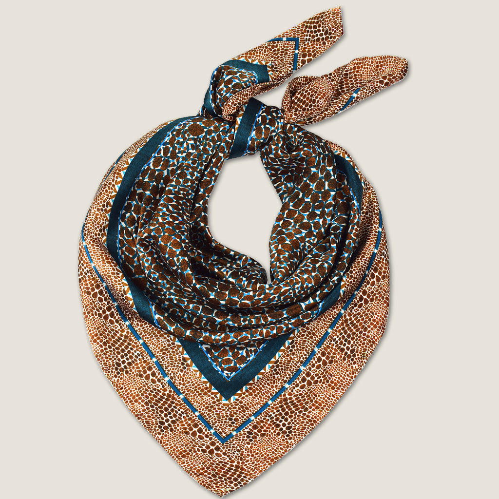 Laslett England silk scarf folded into triangle, showing teal border and bronze animal print edges.