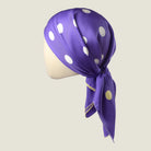Laslett England Solitaire Violet Foulard knotted as a head covering, violet silk satin with lemon polka dots.