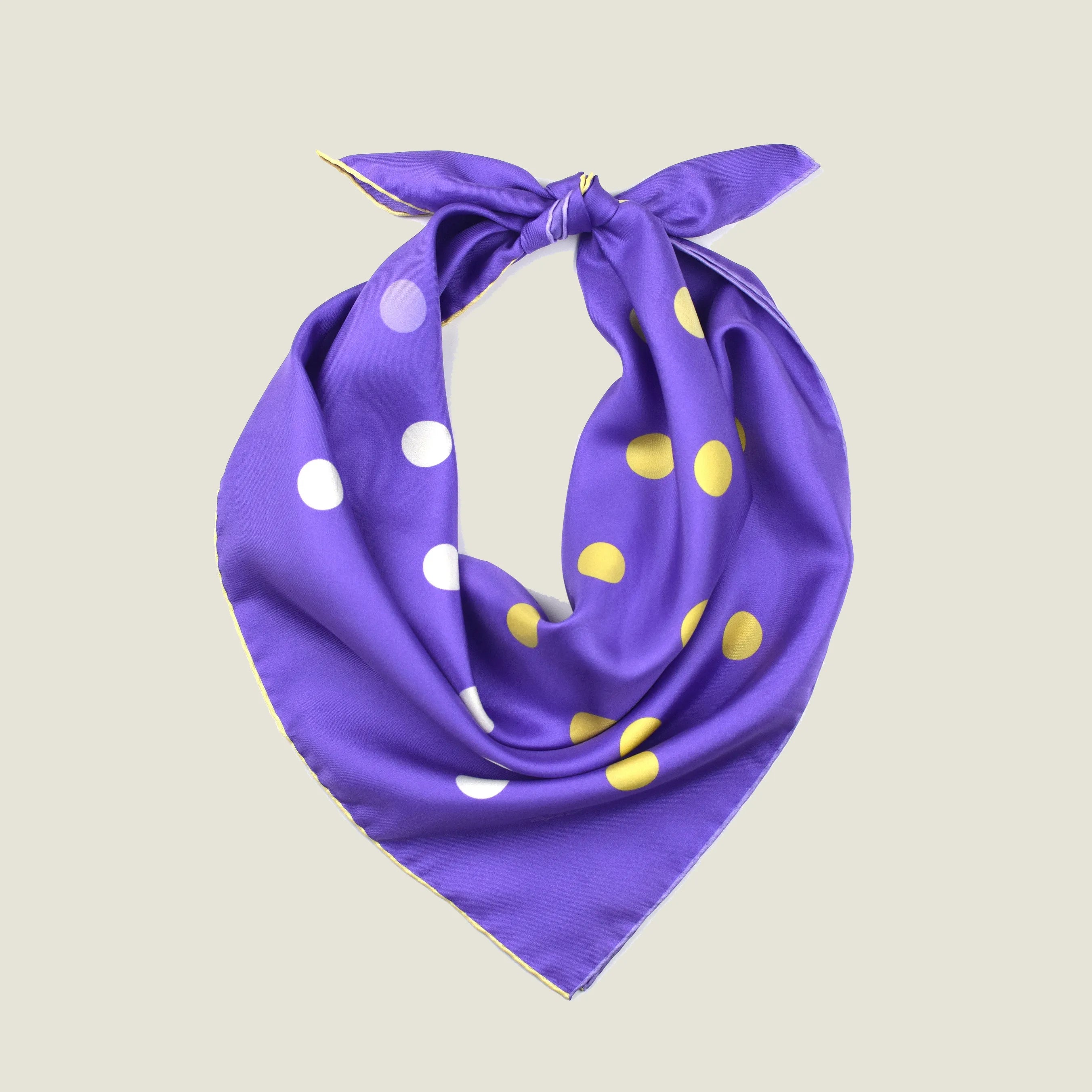 Laslett England Solitaire Violet Foulard folded into triangle, showing violet silk satin with lemon and cream polka dots and cream hand-rolled edge. 
