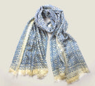 Laslett England Starry Cream Laslett Wrap folded and hanging, showing cream and blue micro-star print on superfine wool with hand-fringed hem
