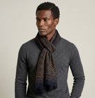 Laslett England Starry Midnight Laslett Wrap worn looped at neck by male model in grey coat, showing deep blue-black ground with bronze star printnd