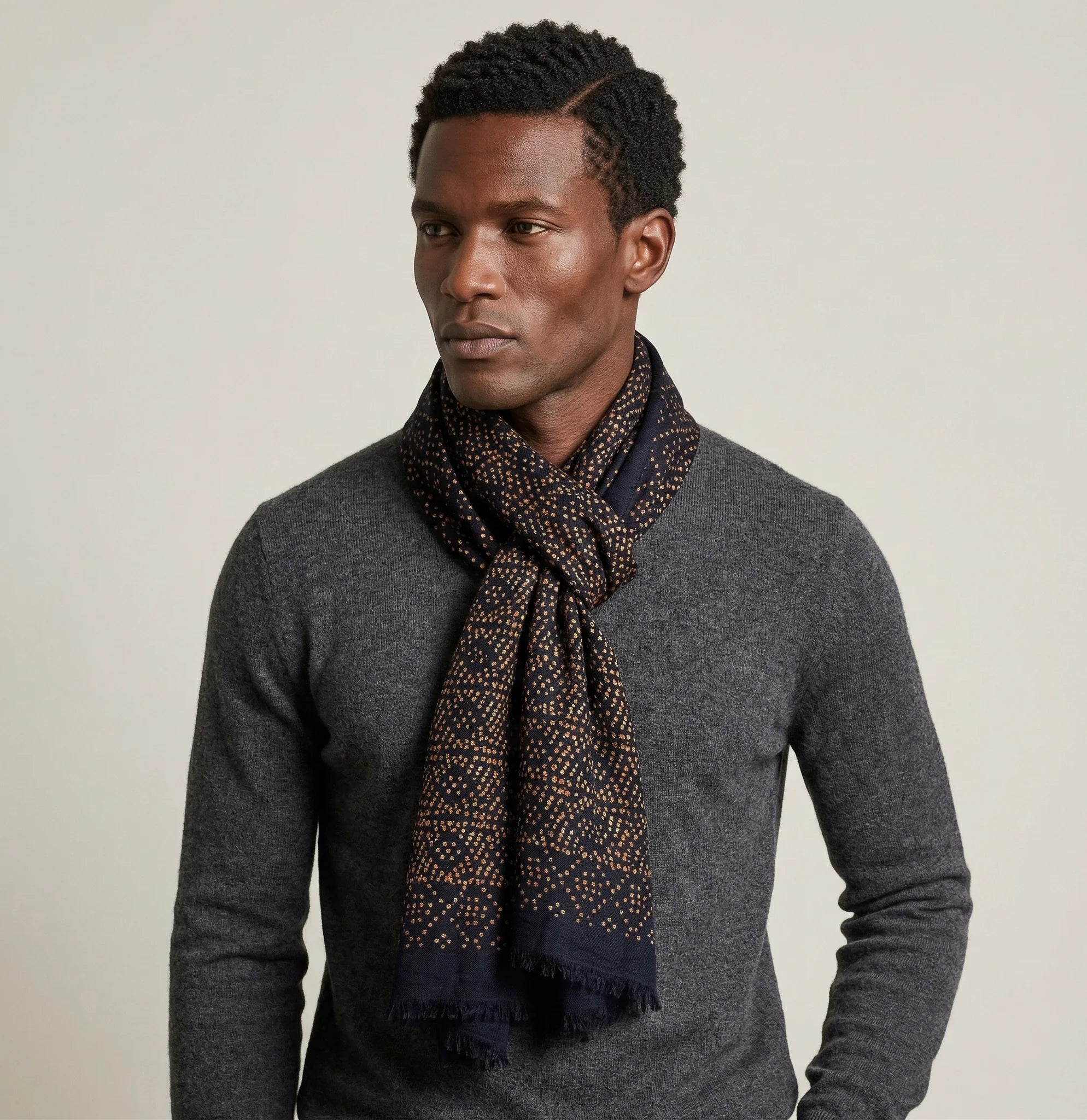 Laslett England Starry Midnight Laslett Wrap worn looped at neck by male model in grey coat, showing deep blue-black ground with bronze star printnd