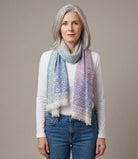 Laslett England Starry Rainbow Laslett Wrap worn draped over shoulders by female model in white top and jeans, showing rainbow micro-star print in pastel tones.