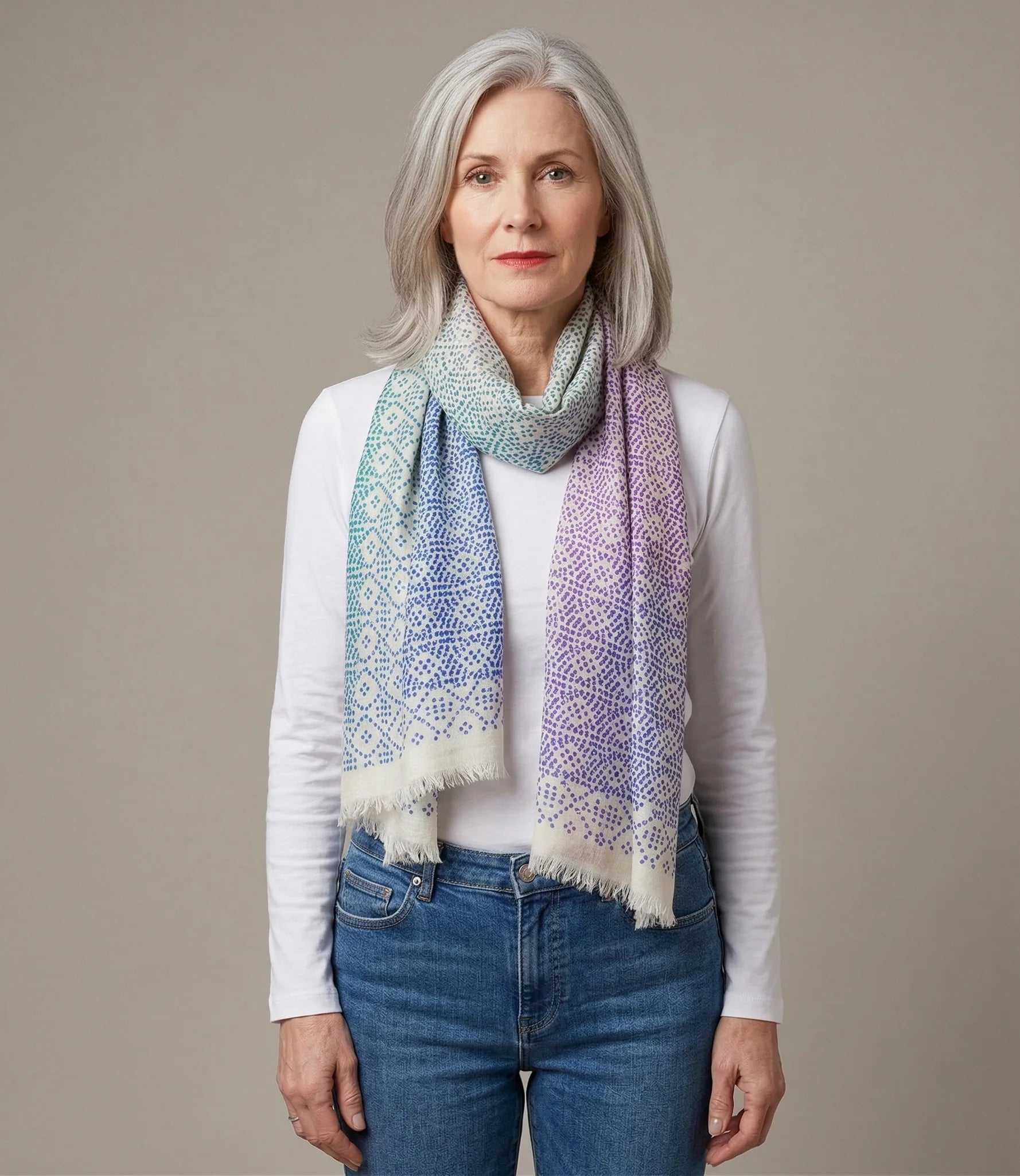 Laslett England Starry Rainbow Laslett Wrap worn draped over shoulders by female model in white top and jeans, showing rainbow micro-star print in pastel tones.