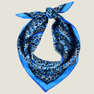 100% silk Tiger Moth Silk Bandana in blue with animal print by Laslett England. Shown knotted at the back against a neutral background. 