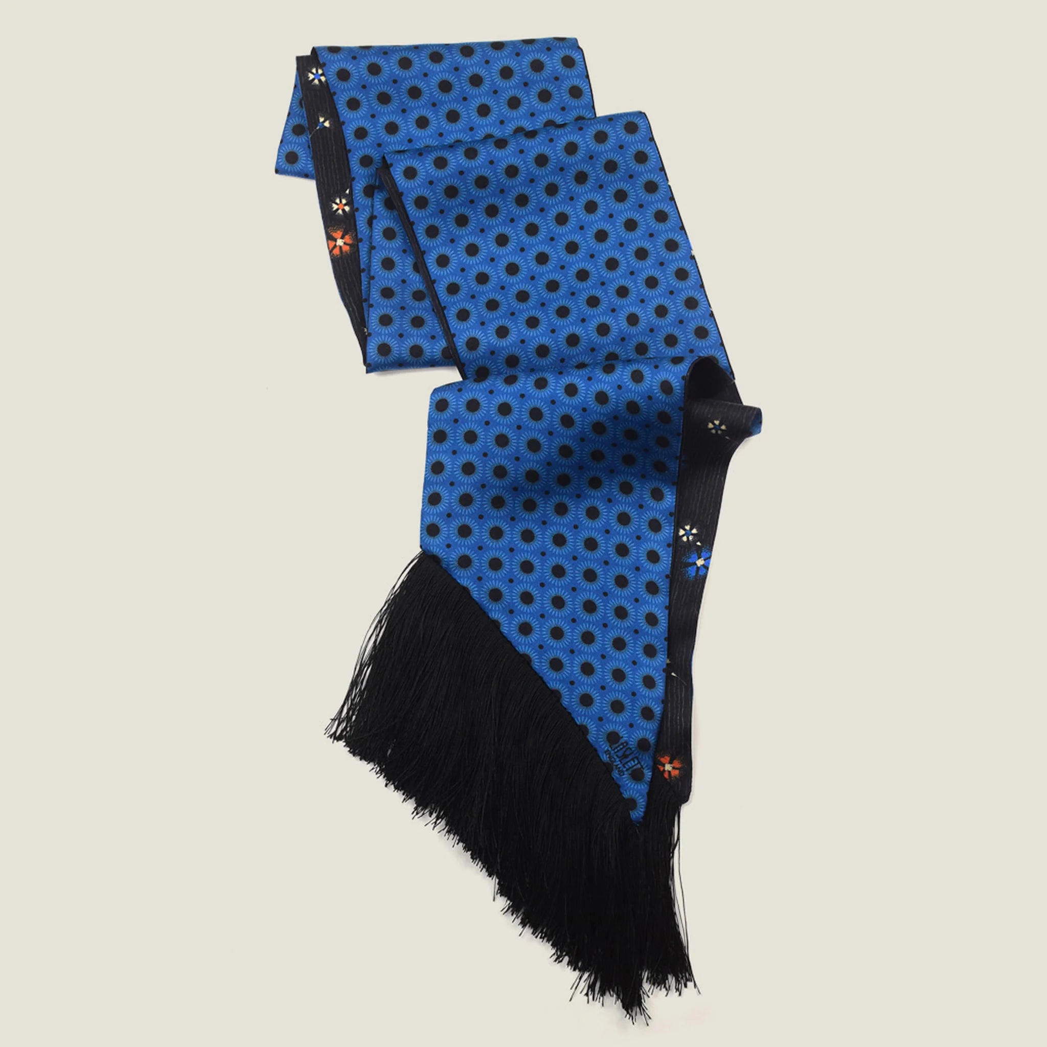 Laslett England Tuxedo Blue Fringed Silk Scarf folded and hanging, showing cobalt blue geometric dot print with black tassel fringe at base.