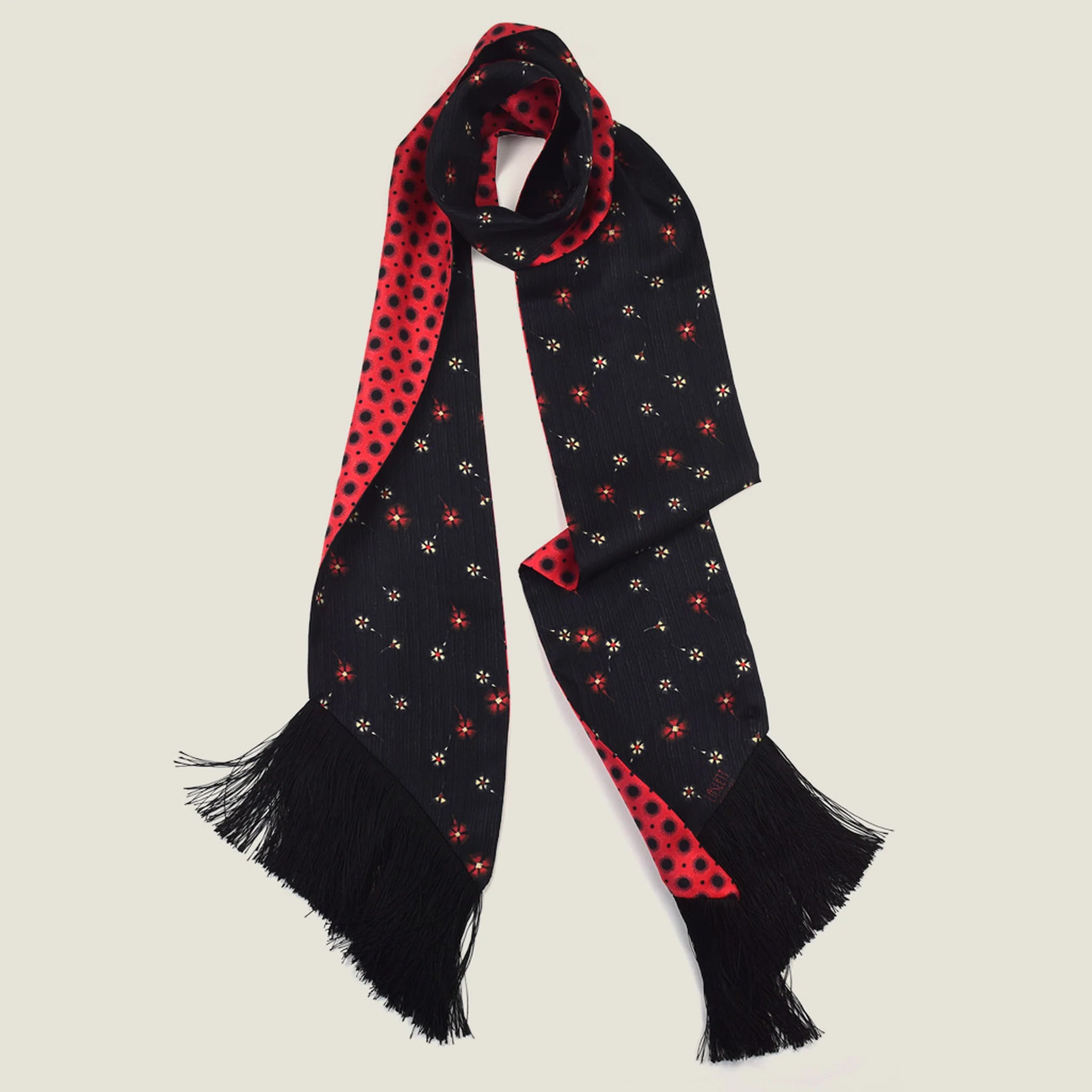 Laslett England Tuxedo Red Fringed Silk Scarf folded and hanging, showing red geometric dot print with black tassel fringe at base.