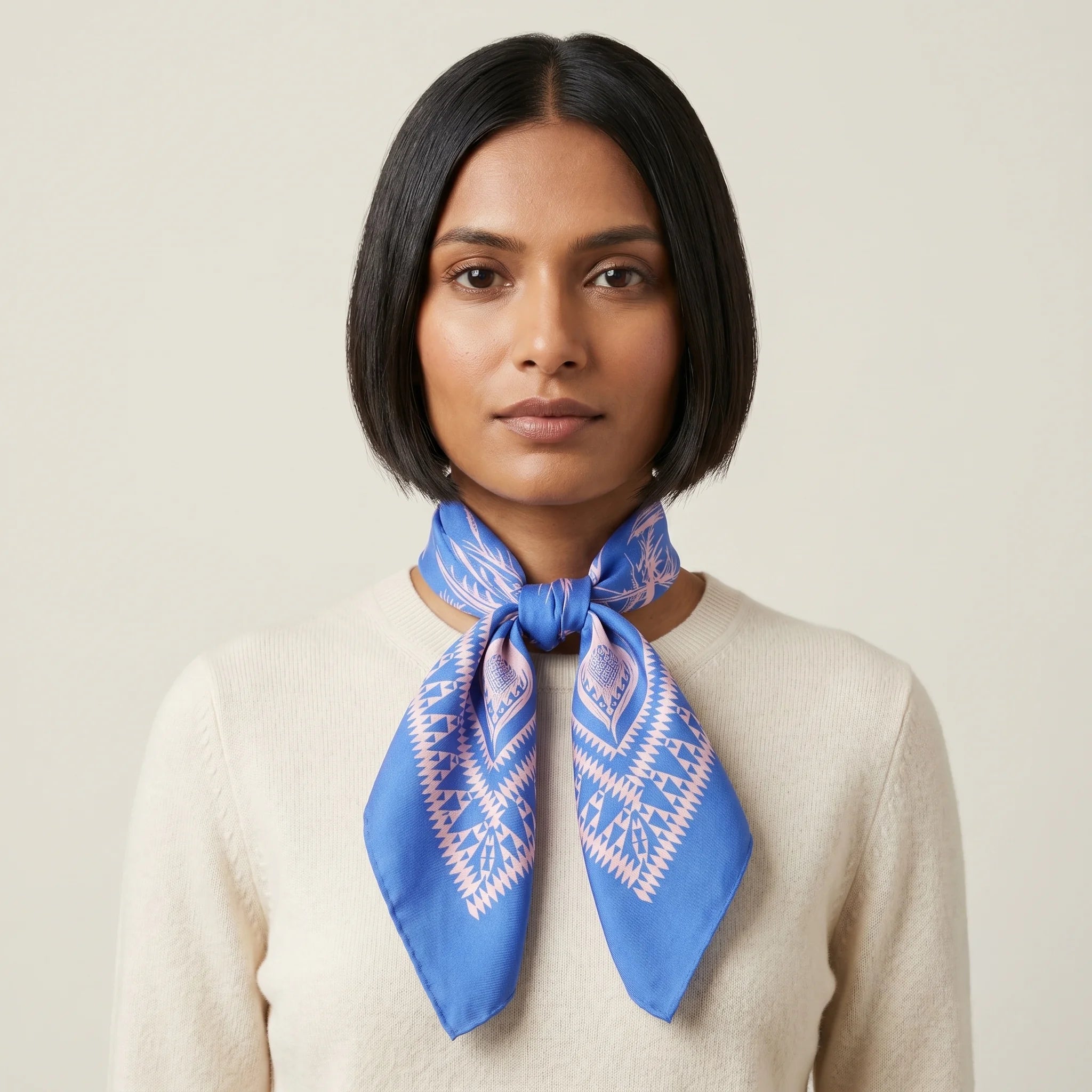 Laslett England Marettimo Cornflower Blue Bandana tied into a knot around a female model's neck. The pink pattern is inspired by botanical and coastal elements. 