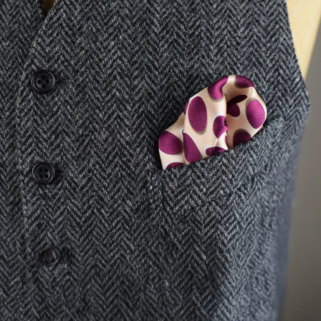 Laslett England Oval Spot Burgundy pocket square shown folded into a tweed waistcoat. 