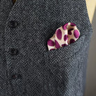Laslett England Oval Spot Burgundy pocket square shown folded into a tweed waistcoat. 