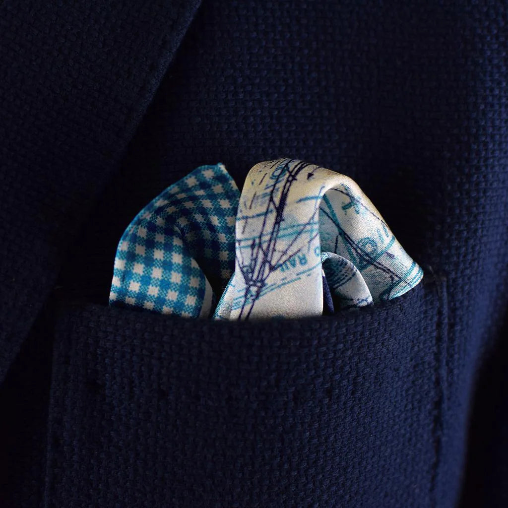 Laslett England Sandpiper Azure pocket square detail, sail plan and rigging print in blue and white with gingham border shown in a navy suit jacket pocket. 