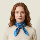 100% silk Tiger Moth Silk Bandana in blue with animal print by Laslett England. Shown knotted in front on a model. 