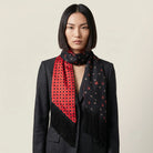Laslett England Tuxedo Red Fringed Silk Scarf worn at neck by female model in navy suit, red side facing outward with black tassel fringe hanging down.